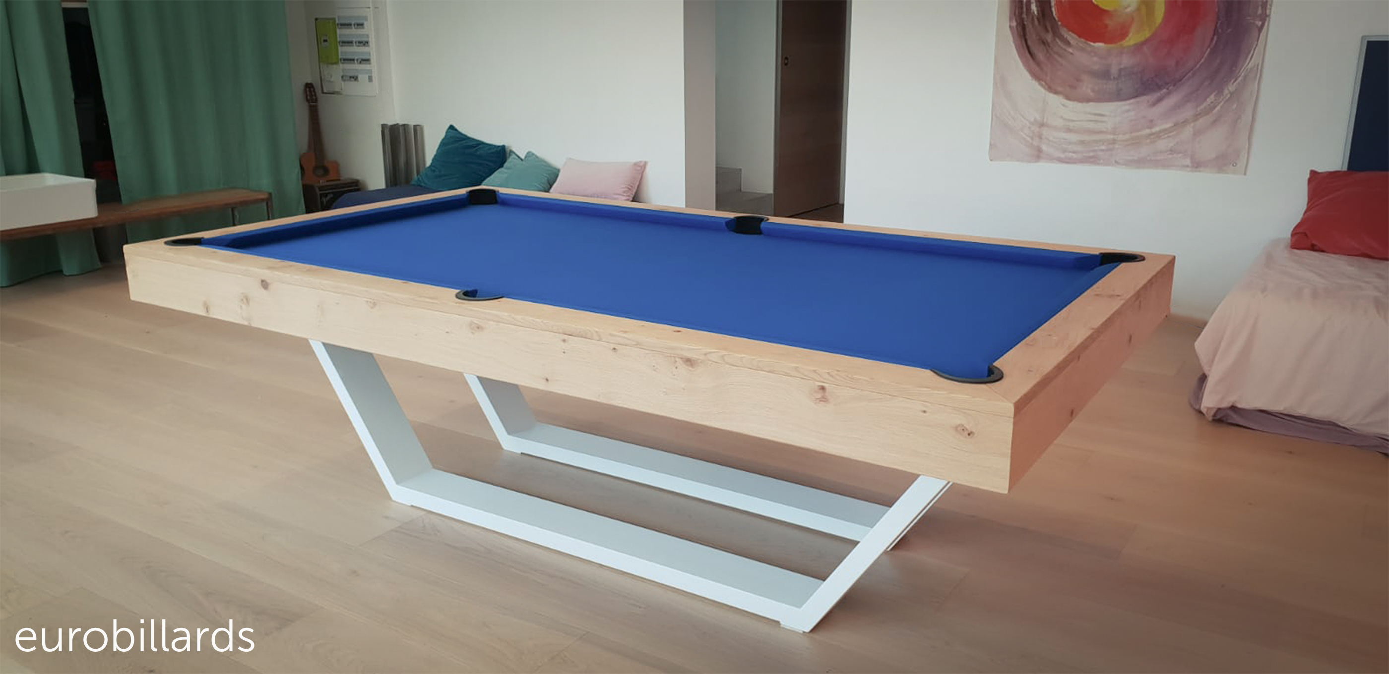 Billard de style néo industriel avec ses 2 pieds métallique blanc qui soutiennent le cadre de jeu en chêne finition naturelle 2x entourant un tissu de jeu bleu roi